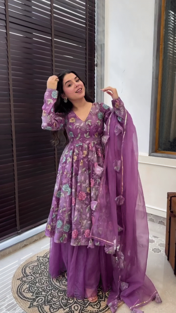 Purple Floral Anarkali Suit Set Featuring V-Neck and Sheer Full Sleeves with Intricate Multicolor Bloom Print, Paired with Matching Flowing Palazzo Pants and a Soft Organza Dupatta Embellished with Floral Tassels and Subtle Golden Border – A Graceful Ethnic Ensemble for Festive and Special Occasions