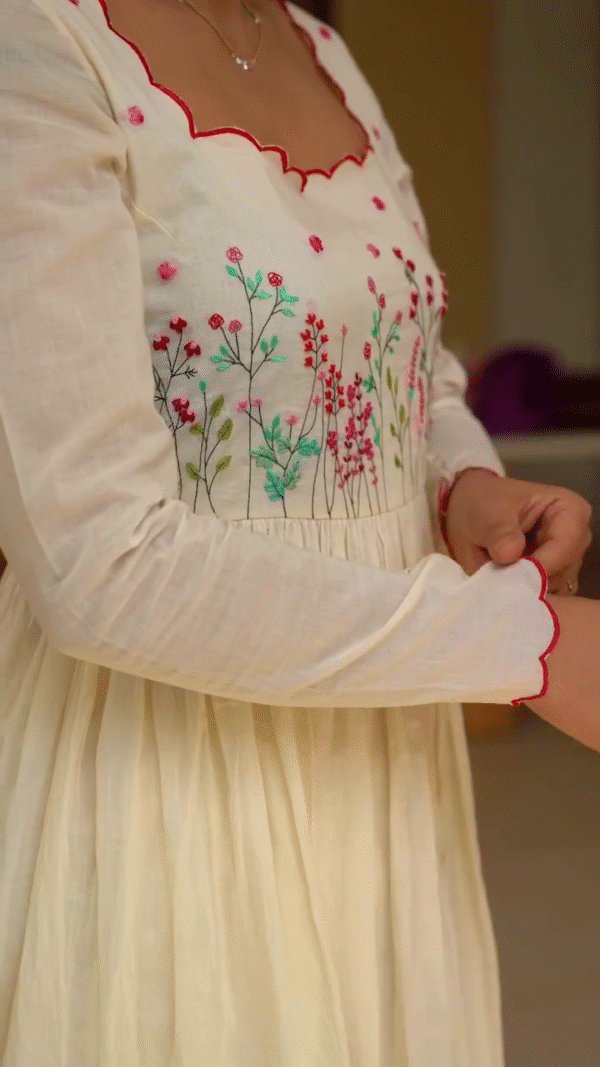 A delicate white ethnic outfit featuring intricate floral embroidery in soft pinks and greens, with a contrasting red scalloped border - Image 2