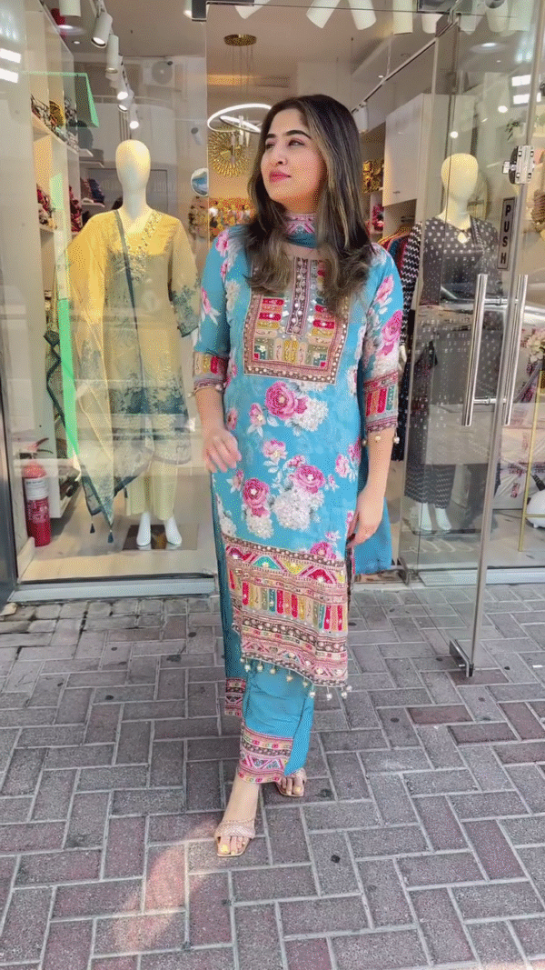 Charming Sky Blue Straight-Cut Suit with Bold Floral Prints and Multicolor Embroidered Neck Panel – Enhanced with Ethnic Motifs, Mirror Work Highlights, and Matching Printed Trousers – A Perfect Pick for Festive Daywear and Cultural Gatherings